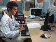 Se aprecia a una persona con bata blanca  sentado frente al ordenador.